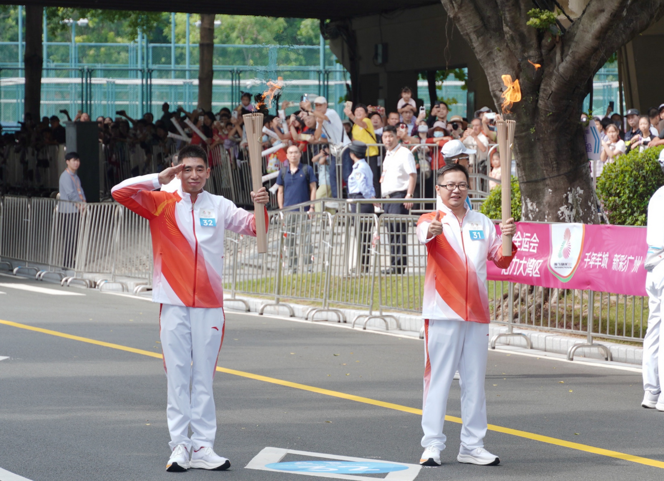 11月2日,十五运会火炬在广州传递,第31棒火炬手吴鹏轩和第32棒火炬手周维亮(左)交接圣火。受访者供图