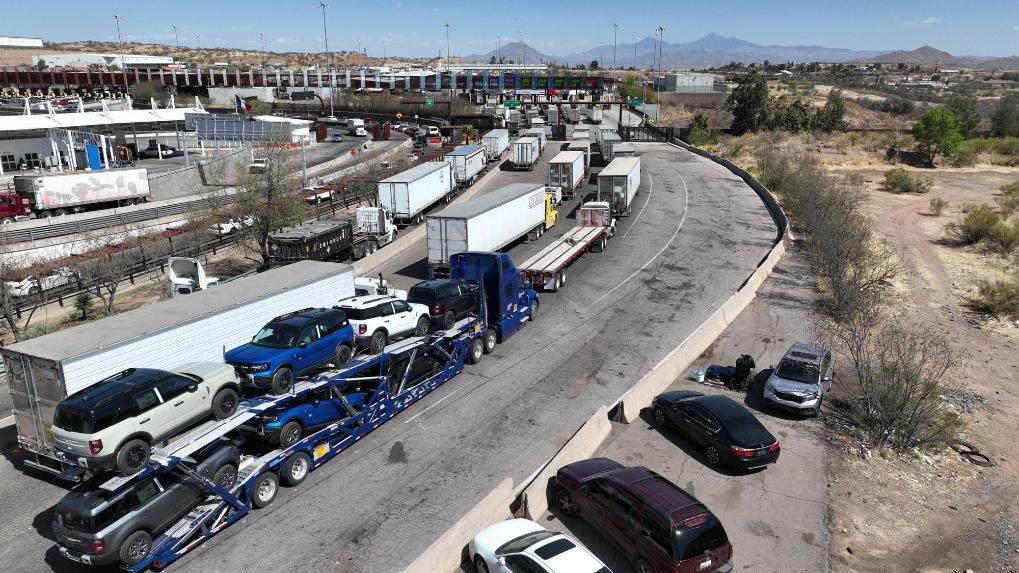 4月2日,在墨西哥索诺拉州诺加莱斯市,一辆装载多辆汽车的运输车(下中)行驶在墨美边境附近的公路上(无人机拍摄)。新华社记者李梦馨摄