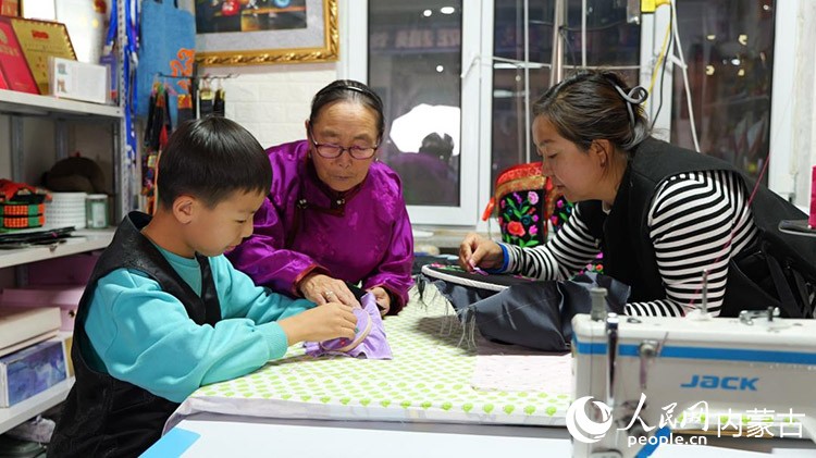 71岁的萨仁格乐正教着她的女儿和外孙做蒙古靴刺绣。苏米雅摄