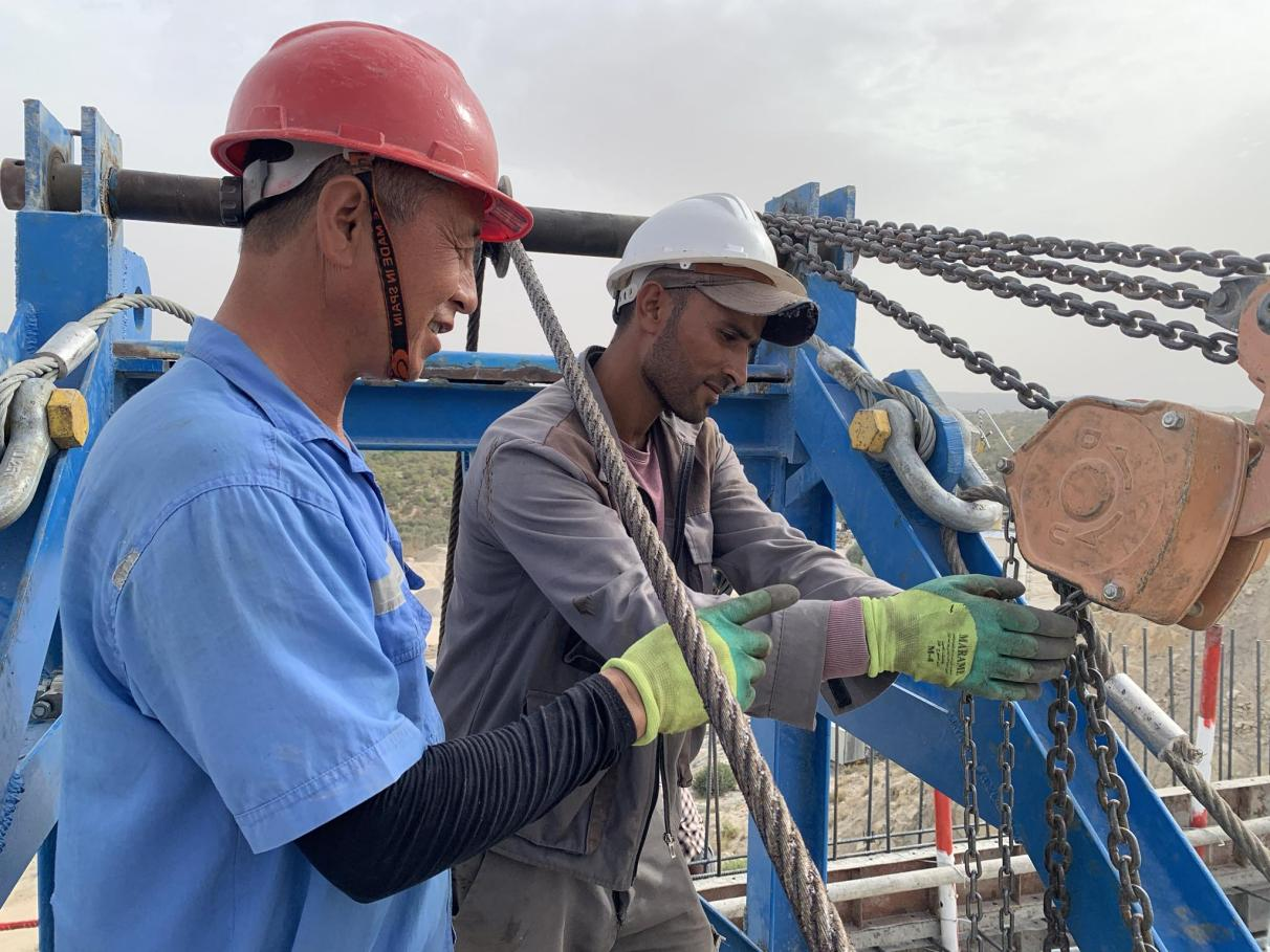 当地员工在中国师傅带领下检查钢丝绳。中国电建供图